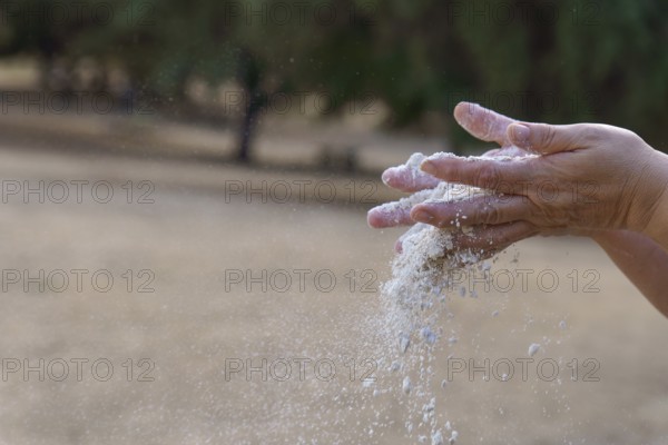 Hands pouring white sand, symbolizing the passage of time, impermanence, and the fleeting moments
