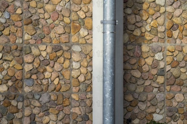 Borken, NRW, Germany, RPebble stone wall with a vertical metal drainpipe creating an interesting