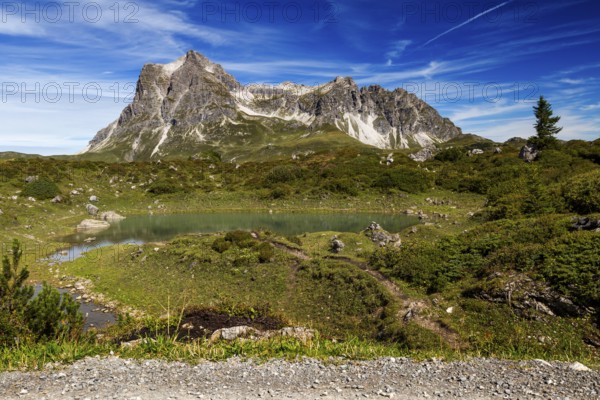 A small lake nestled in an alpine landscape with the distinctive Großer Widderstein mountain,