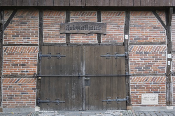 Wooden and brick gate of a medieval half-timbered house with rustic sign, Münsterland, North