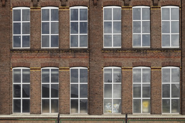 Symmetrical façade of an old brick building with large industrial windows, former Germania cotton