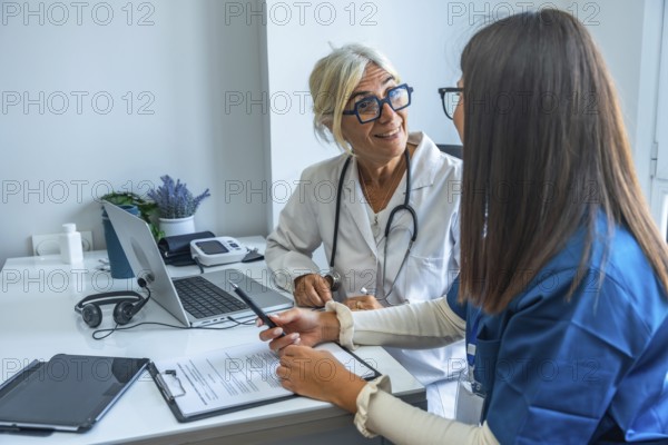 Two medical professionals are discussing important healthcare documents and using a laptop in a