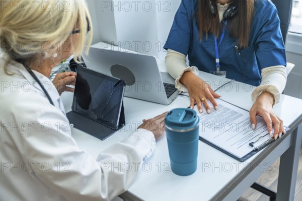 Healthcare team reviewing digital tablet and medical records, discussing patient care plans and