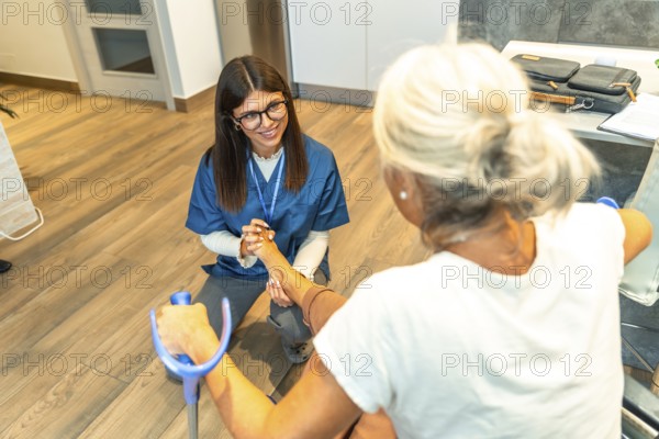 Healthcare professional assisting an elderly patient with physical rehabilitation exercises on her