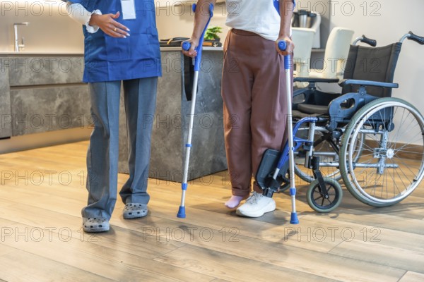 Healthcare professional assisting a patient learning to walk with crutches, providing support
