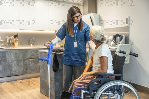 Young female caregiver in scrubs assisting a senior woman in a wheelchair, providing home