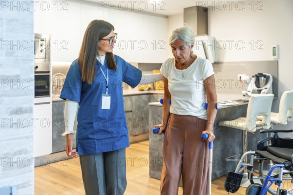Home care nurse supports elderly woman with crutches during rehabilitation exercises at home,