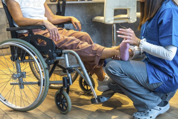 Physiotherapist providing physical therapy to a senior patient sitting in a wheelchair, offering