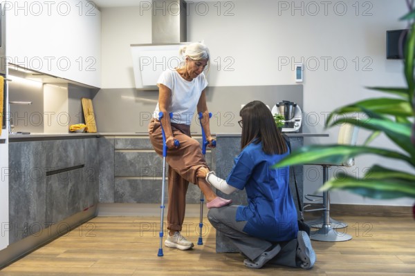 Healthcare professional guiding elderly woman with crutches during home physiotherapy session,