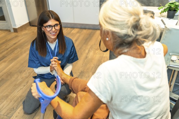Happy young nurse providing professional foot physical therapy and care to an elderly woman using