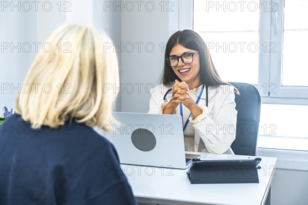 Young female doctor wearing a lab coat and stethoscope, smiling while actively listening to a