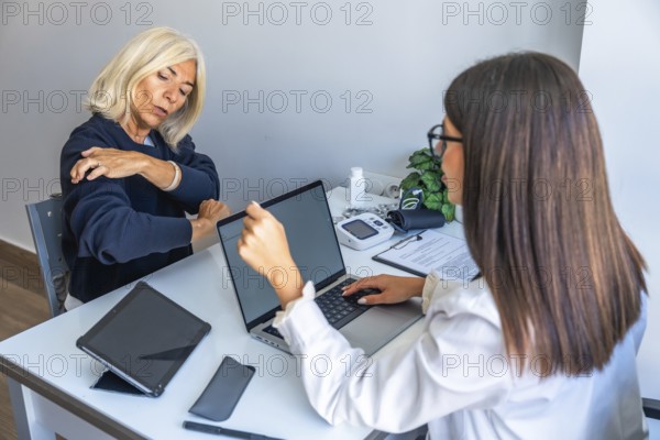 Female doctor consulting with elderly woman about shoulder pain and treatment options, using a