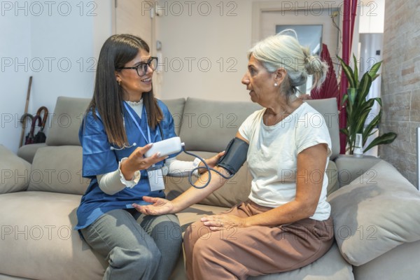 Healthcare professional checking blood pressure for an elderly woman in her home, providing