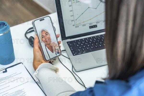 Woman having an online telemedicine consultation with a senior female doctor on a mobile phone,