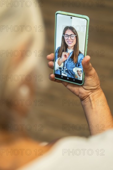 Senior woman holding smartphone for a telemedicine video call with doctor, receiving virtual