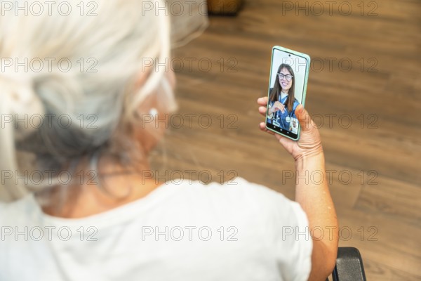 Senior woman is using a smartphone for a distant video consultation with a female doctor,