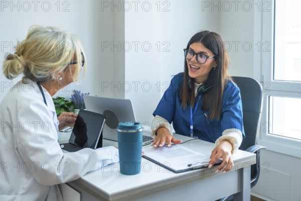 Healthcare professionals, a doctor in a lab coat and a nurse in scrubs, sitting at a desk and