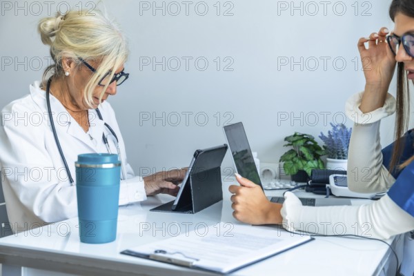 Two female medical professionals are collaborating and working together at a desk, utilizing