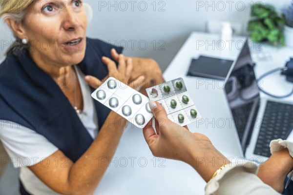 Doctor hand holding two blister packs of pills, one with green capsules and one with silver