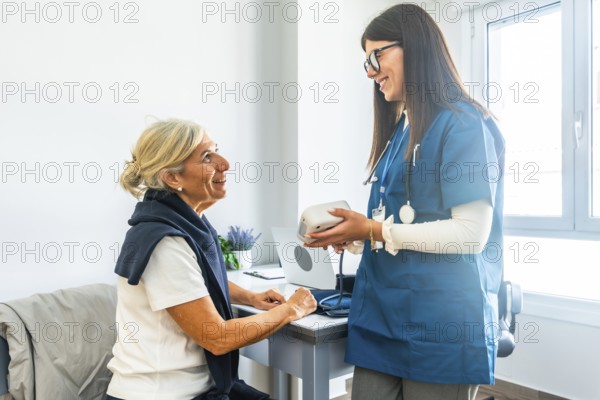 Doctor talking to senior woman, holding a blood pressure monitor, and preparing to check her vitals