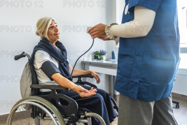 Nurse monitoring blood pressure of an elderly woman using a medical device while she is sitting in