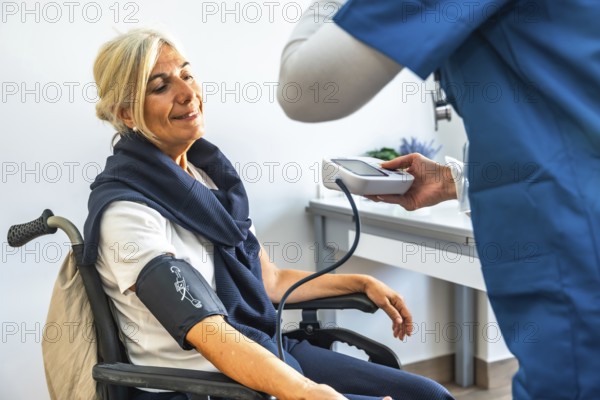 Senior woman in a wheelchair having her blood pressure measured by a medical professional,