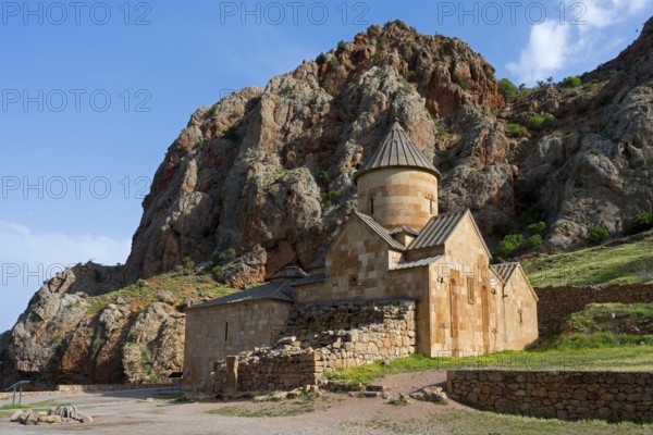 A stone church nestled in a rocky landscape with blue sky in the background, Noravank monastery,