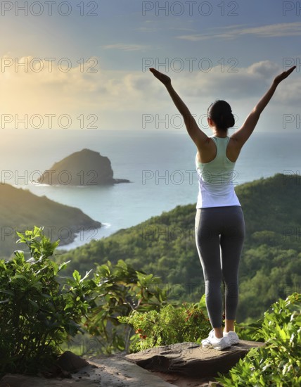 A woman is standing on a mountain top, looking out over the ocean. She is wearing a white tank top