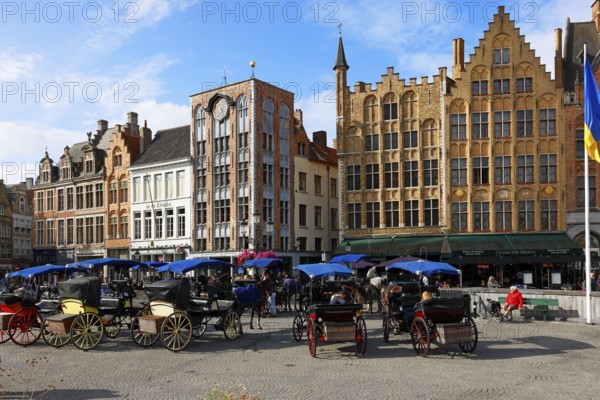 Historic houses on the market square in the old town of Bruges with horse-drawn carriages, Grote