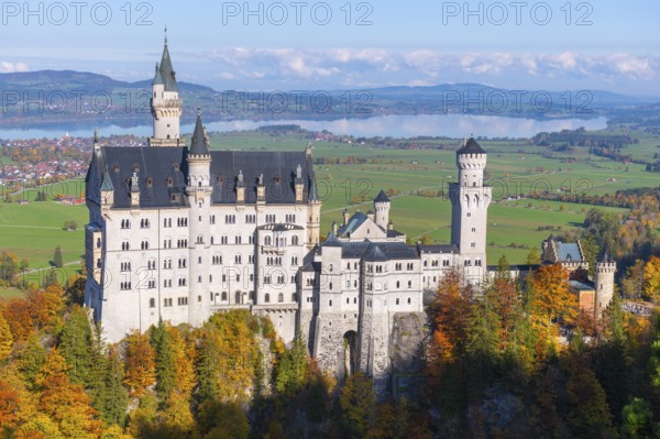 Impressive Neuschwanstein Castle stands majestically in an autumn-colored landscape with