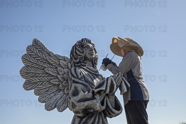 Chandler, Minnesota, Artist Primi Monteiga re-paints her concrete sculpture of an angel in the