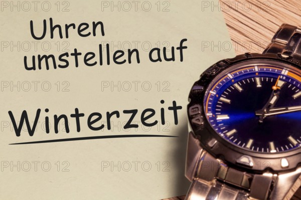 (photo montage) Time change winter time: close-up of a wristwatch and a note with the text CHANGE