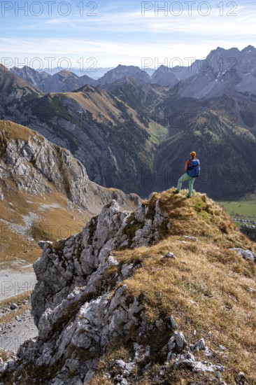 Hiker stands on a rock and looks into Ta, hiking to Gamsjoch, down the Ahornboden valley, eastern
