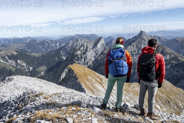 Two hikers on the summit of Gamsjoch look at the mountains, eastern Karwendel, Tyrol, Austria