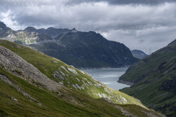 View of a lake in a valley surrounded by mountains, dramatic sky with low-hanging clouds, Lac des