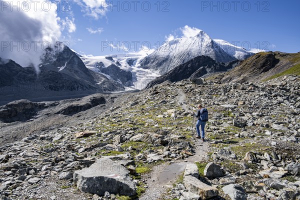 Hiker on rocky path with impressive views of snow-covered mountain landscape, Mont Blanc de Cheilon