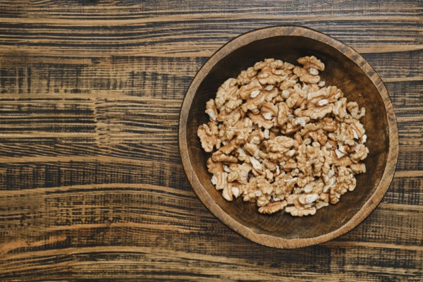 A wooden bowl with peeled walnuts, showcasing their rich texture and natural color on a rustic