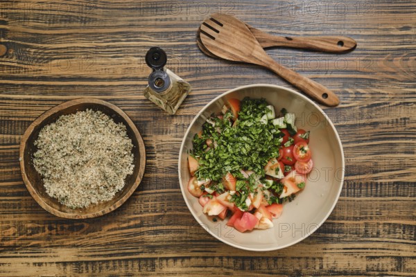 Chopped tomatoes and fresh herbs in a bowl ready for mixing. A bowl with crushed walnuts is nearby,