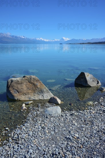 Large boulders on a sunny lake with mountain backdrop, Lake Pukaki Viewpoint, Pukaki, Canterbury,