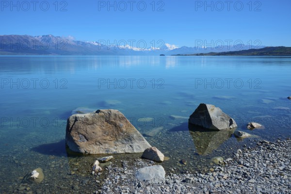 Large stones on clear lakeside with mountains in the background, Lake Pukaki Viewpoint, Pukaki,