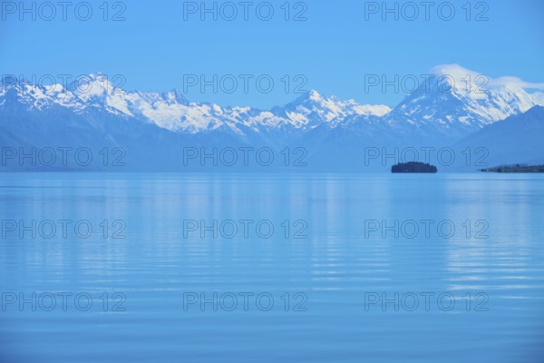 Expansive view of a tranquil lake with snow-capped mountains Mount Cook and an island, Lake Pukaki