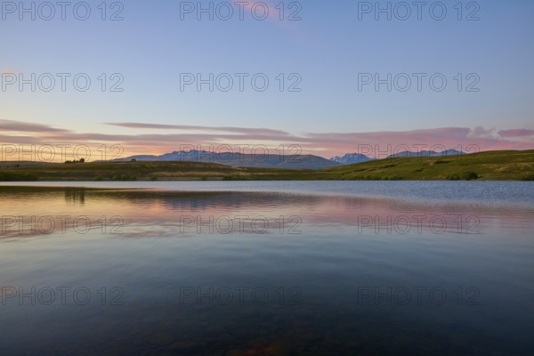 Lake with calm water and mountains in the background with a pink-blue sky, Lake McGregor, Tekapo,