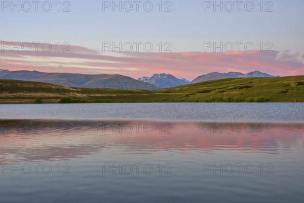 Calm lake with mountains and pink morning sky in the background, Lake McGregor, Tekapo, Canterbury,