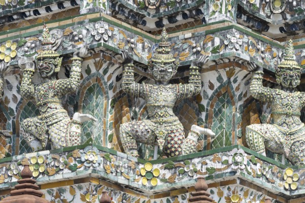 Demon figures (yaksha) supporting the central prang of Wat Arun decorated with colorful ceramic and