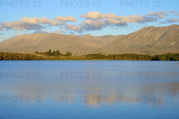 Extensive seascape in evening light with rolling mountains and cloudy skies, Lake McGregor, Tekapo,