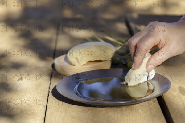 Hand dipping fresh homemade bread into healthy extra virgin olive oil, a staple of homemade