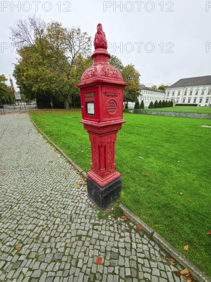 Historic red fire alarm column on cobblestones on the roadside of the Federal President's office,