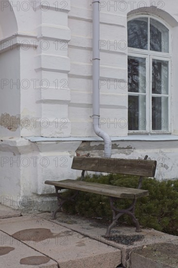 Empty old wooden bench against weathered white stone building, Mustio, Finland
