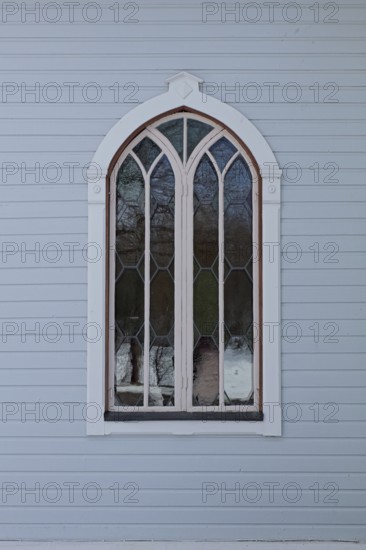 Closed old arched window with white frame on a light blue board wall, Mustio, Finland