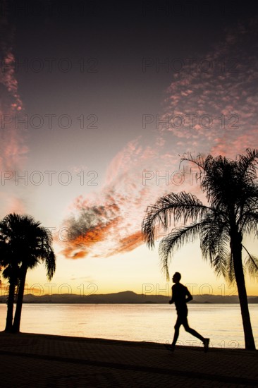 People walking on the sidewalk of Beira Mar Norte Avenue at sunset. Florianopolis, Santa Catarina,